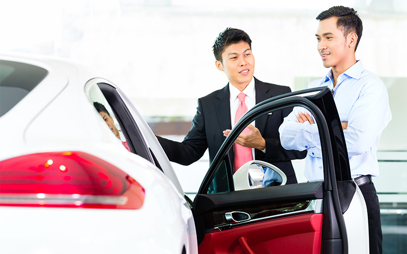 M Motors consultant explaining PARF rebate benefits to car buyer.