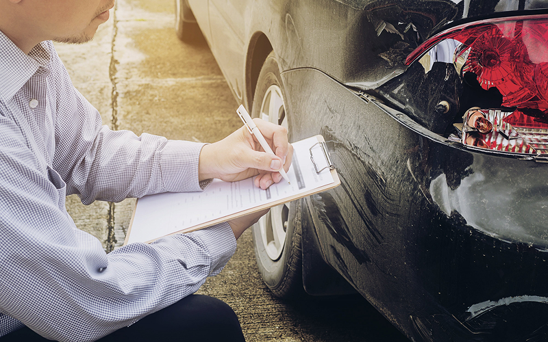 Claims adjuster documenting damage for a motor insurance claim.