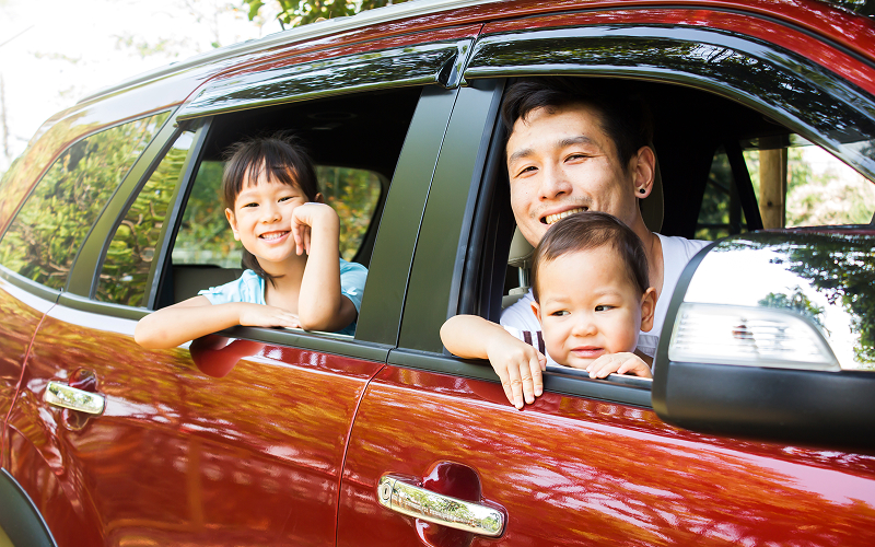 Asian-family-smiling-inside-a-red-7-seater-car