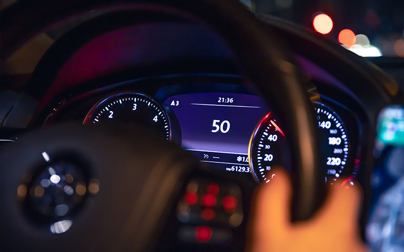 Illuminated car dashboard display showing vehicle speed and odometer reading.