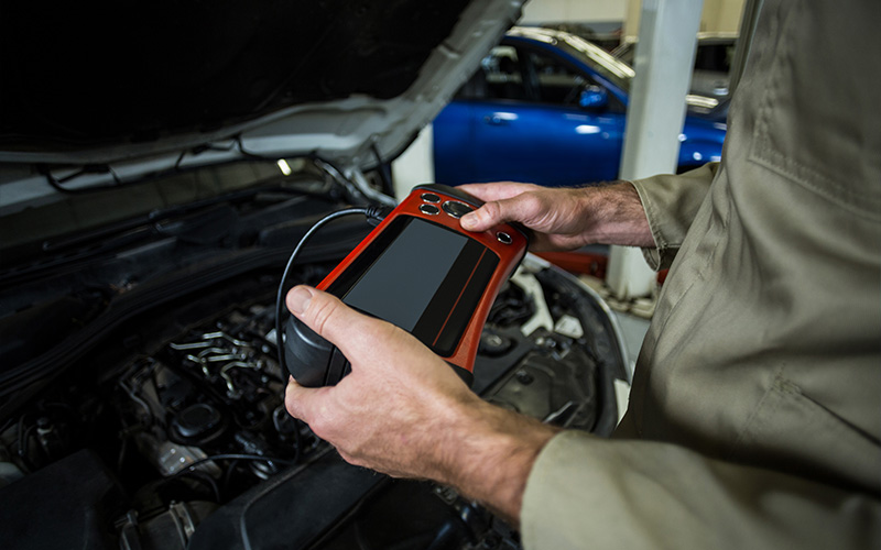 Mechanic using diagnostic scanner tool on electric vehicle system.