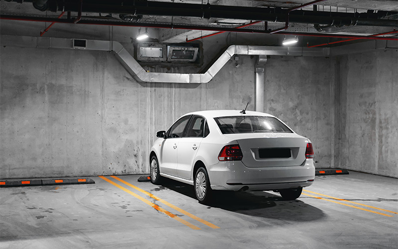 White leased car parked in an underground garage spot.